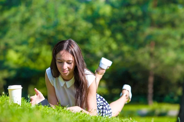 Молодая девушка пишет в блокноте в парке — стоковое фото