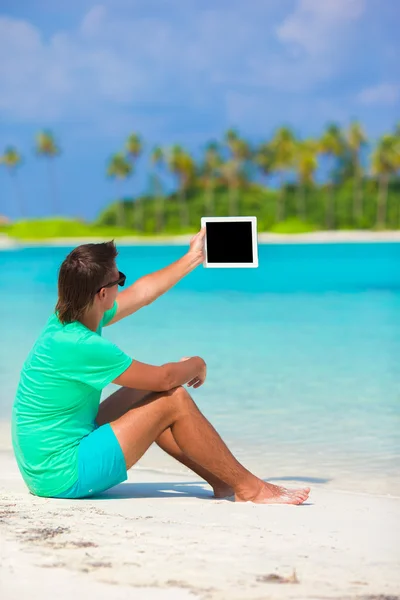 Młody mężczyzna pracujący z laptopa na tropikalnej plaży — Zdjęcie stockowe
