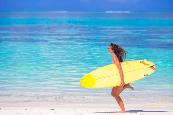 Glückliche wohlgeformte Surferin am weißen Strand mit gelbem Surfbrett — Stockfoto