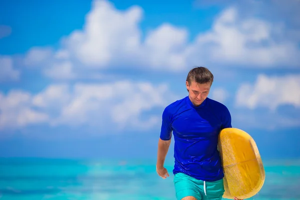 Feliz joven surfista en playa blanca con tabla de surf amarilla — Foto de Stock