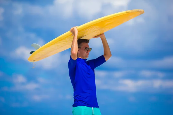 Щасливий молодий серфінг чоловік на білому пляжі з жовтим дошкою для серфінгу — стокове фото