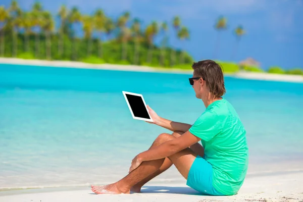 Giovane che lavora con il computer portatile sulla spiaggia tropicale — Foto Stock