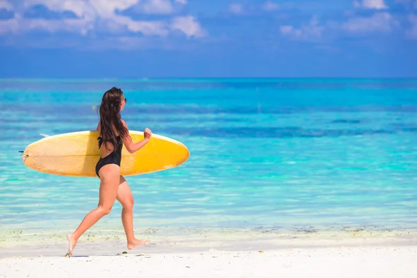 Gelukkige fraai gevormde surf vrouw op witte strand met gele surfboard — Stockfoto