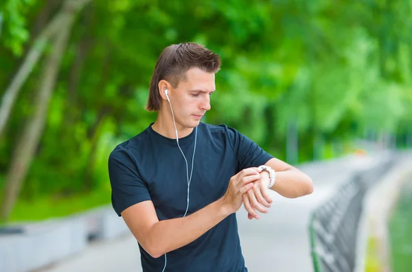 Läufer schaut auf Smart Watch Pulsmesser, der während des Laufens Pause macht — Stockfoto