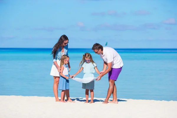 Familia feliz con mapa encontrar el camino en la playa — Foto de Stock