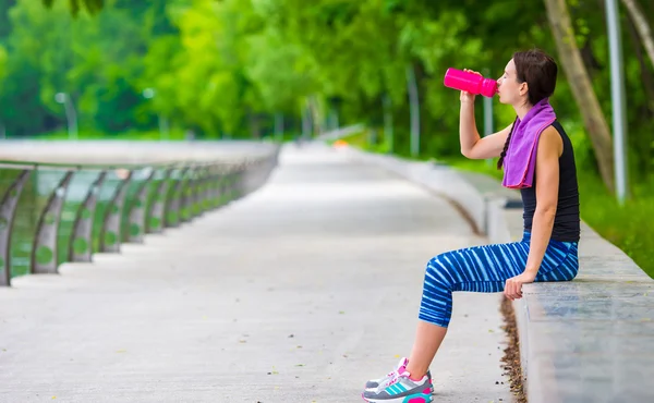 Joven mujer fitness activa con esterilla y botella de agua al aire libre — Foto de Stock