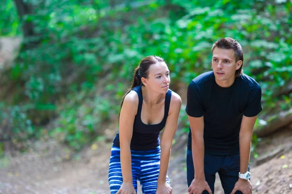 Correr pareja activa tomando un descanso durante el entrenamiento al aire libre en el parque —  Fotos de Stock