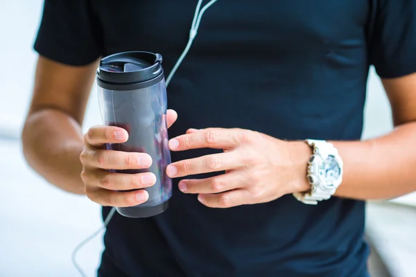 Monitor de ritmo cardíaco inteligente de primer plano y botella de agua en manos masculinas — Foto de Stock