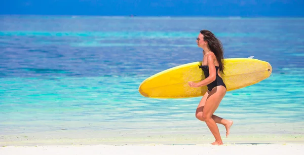 Feliz mujer de surf bien formada en la playa blanca con tabla de surf amarilla — Foto de Stock