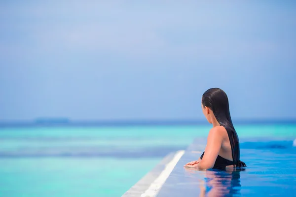 Jonge vrouw genieten van water en rust in zwembad buiten — Stockfoto