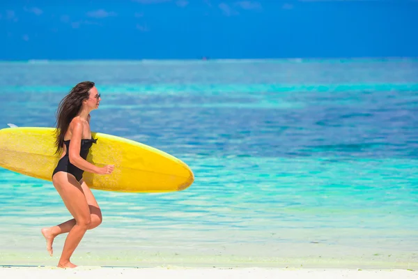 Gelukkige fraai gevormde surf vrouw op witte strand met gele surfboard — Stockfoto