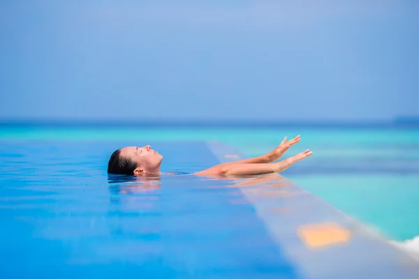 Jonge vrouw genieten van water en rust in zwembad buiten — Stockfoto