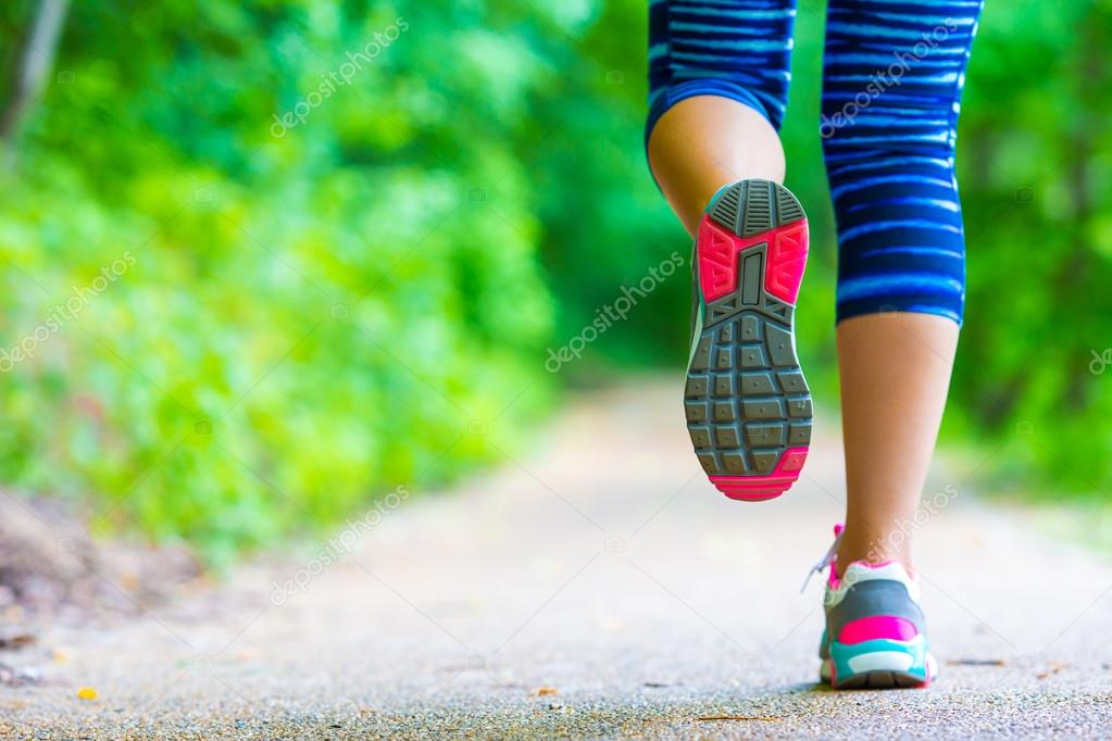 Close-up on shoe of athlete runner woman feet running on road 