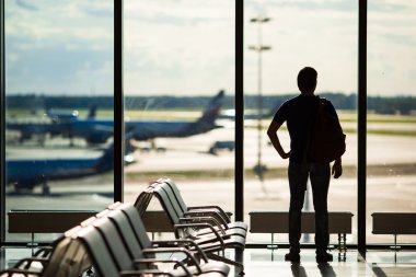 Silhouette of a man waiting to board a flight in airport clipart