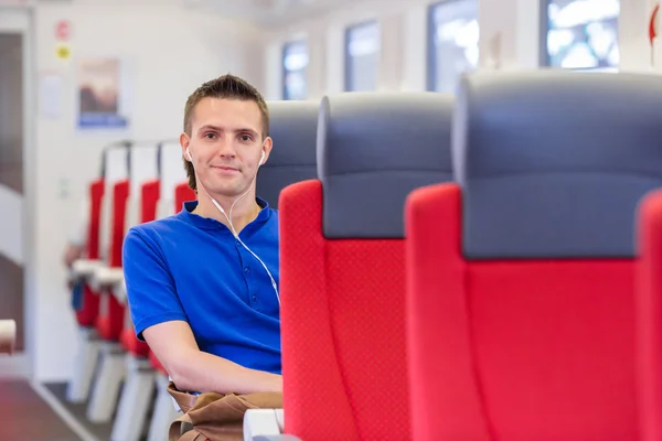 Junger glücklicher Mann mit dem Zug unterwegs — Stockfoto