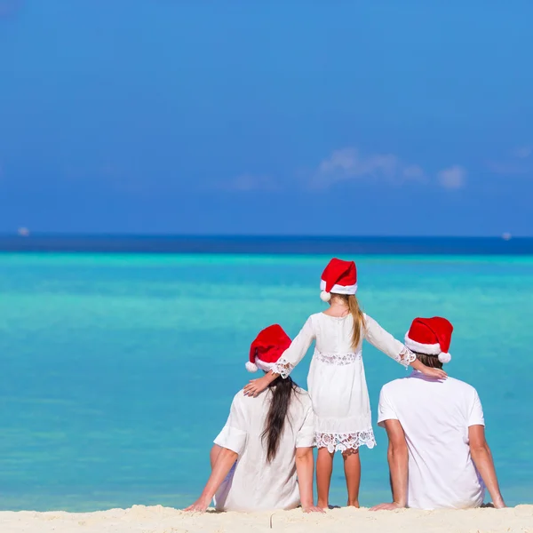 Gelukkige familie in Santa hoeden op strand tijdens de kerstvakantie — Stockfoto