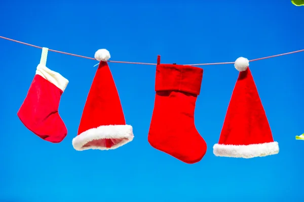 Concetto di Natale: cappelli di Babbo Natale e calza sfondo cielo blu — Foto Stock