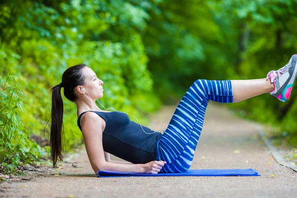Молодая улыбающаяся женщина делает спортивные упражнения на открытом воздухе — стоковое фото