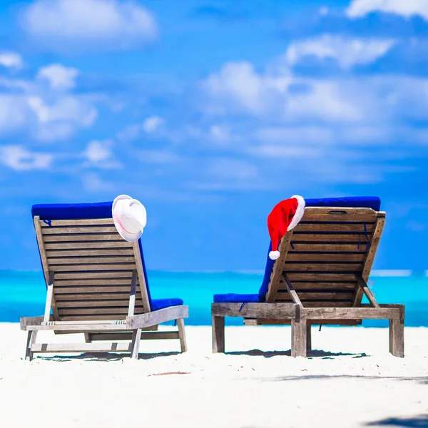 Concetto natalizio: lettini da spiaggia con Babbo Natale rosso e cappelli di paglia sullo sfondo bellissimo mare turchese — Foto Stock