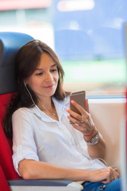 Mutlu kız müzik dinlemek ve tren ile seyahat mesajı okumak