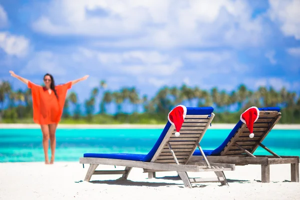 Concepto de Navidad: tumbonas de playa con sombreros rojos de Santa y hermosa chica durante las vacaciones tropicales — Foto de Stock