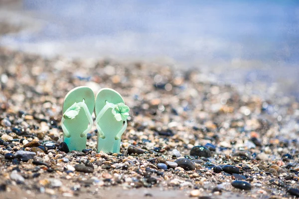 Kids flip flops on beach in front of the sea — Stock Photo, Image