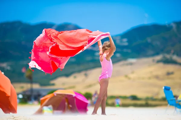 Cute dziewczynka zabawy działa z ręcznikiem na tropikalnej plaży z białym piaskiem i turkusową ocean wody — Zdjęcie stockowe