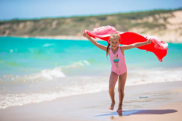 小さな女の子は熱帯の休暇中にビーチタオルで楽しみを持っています — ストック写真