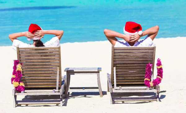 Young couple in Santa hats relaxing on beach during Christmas vacation — Stock Photo, Image