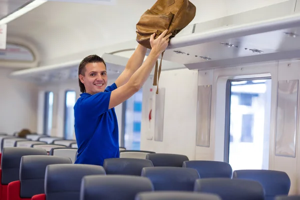 Junger Kaukasier stellt Gepäck im Flugzeug ins oberste Regal — Stockfoto