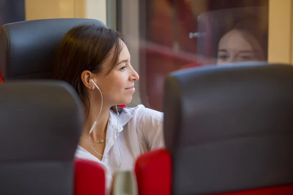 Jeune fille heureuse écoutant de la musique voyageant en train — Photo