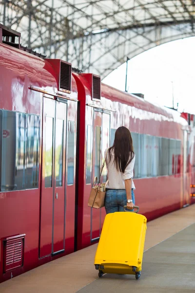 Unga kaukasiska kvinna med bagage vid stationen reser med tåg — Stockfoto