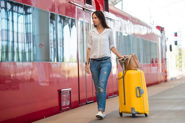 Junge glückliche Frau mit Gepäck am Bahnhof — Stockfoto