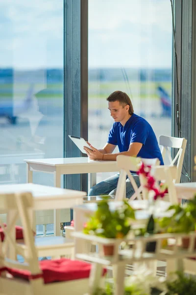 Young man working with laptop at airport cafe waiting boarding — Stock Photo, Image