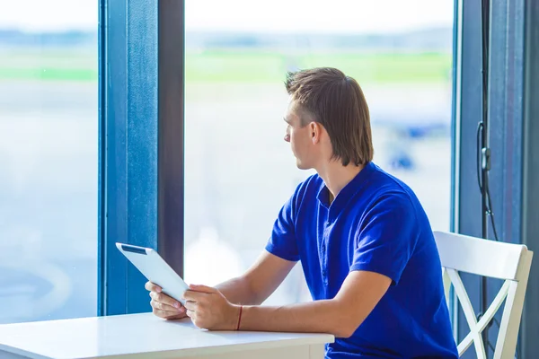 Joven con portátil en la cafetería del aeropuerto mientras espera el embarque —  Fotos de Stock