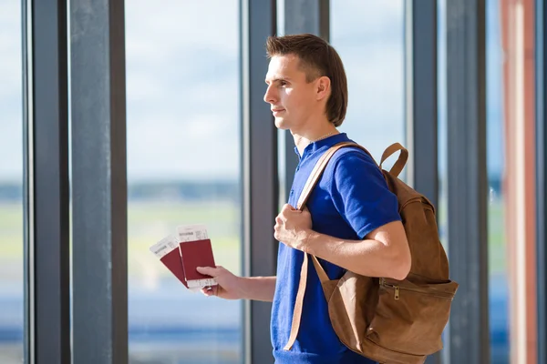 Young man holding passports and boarding pass at airport — Stock Photo, Image