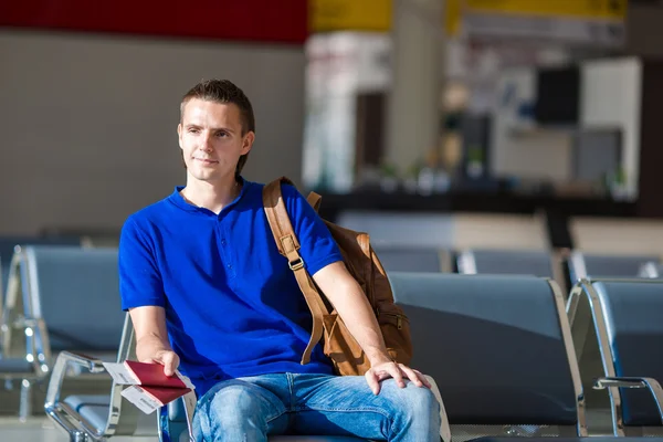 Young man holding passports and boarding pass at airport — Stock Photo, Image