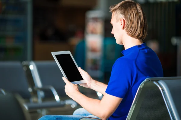 Jonge man met laptop op de luchthaven tijdens het wachten voor instappen — Stockfoto