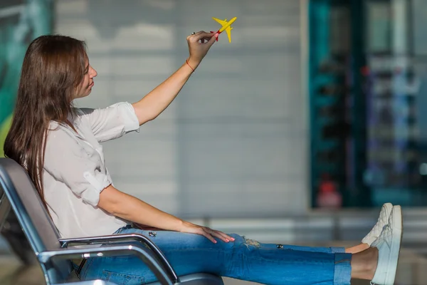 Happy woman with small model airplane and passports in airport — Stock Photo, Image