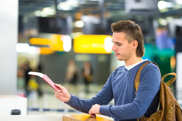 Beautiful man with passports and boarding passes at the front desk at airport — Stock Photo, Image