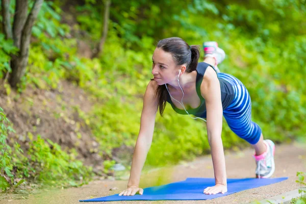 Młoda kobieta uśmiechający się robi sportowy ćwiczenia na zewnątrz — Zdjęcie stockowe