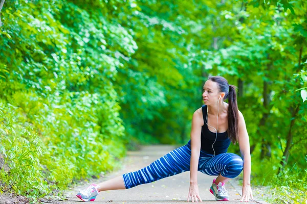 Joven mujer sonriente haciendo ejercicios deportivos al aire libre — Foto de Stock