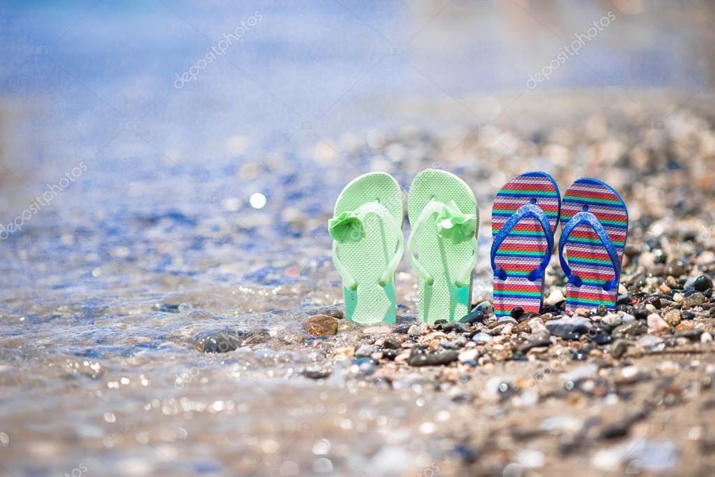 Kids flip flops on beach in front of the sea Stock Photo by ©d