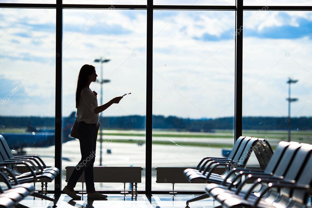 Silhouette of woman in an airport lounge waiting for flight aircraft
