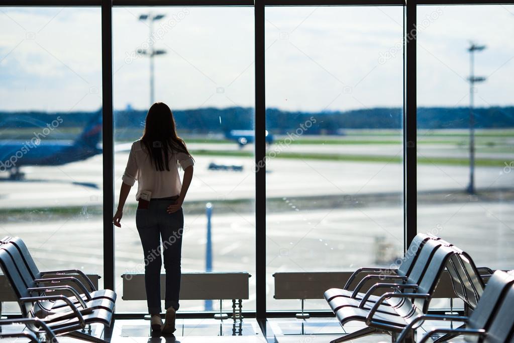 Silhouette of airline passenger in an airport lounge waiting for flight aircraft