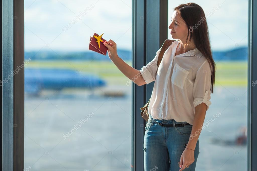 Happy young woman with passports and airplane model at airport 