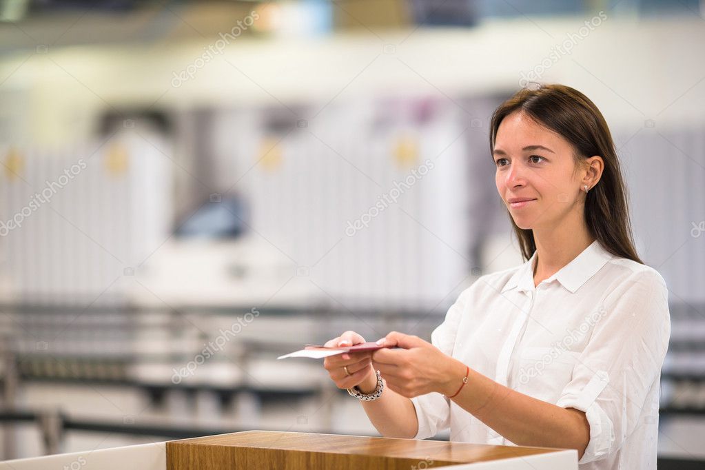 Beautiful woman with passports and boarding passes at the front desk at airport