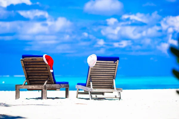 Weihnachtskonzept: Strandliegen mit rotem Weihnachtsmann und Strohhüten Hintergrund schönes türkisfarbenes Meer — Stockfoto