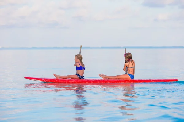 Kleine süße Mädchen schwimmen in den Sommerferien auf dem Surfbrett — Stockfoto