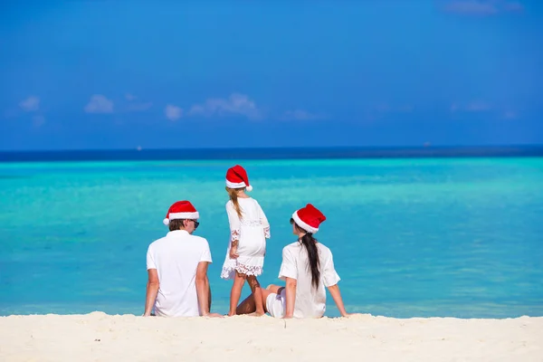 Famiglia felice in Santa Cappelli sulla spiaggia durante le vacanze di Natale — Foto Stock